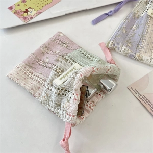 Détail de la pochette à cordon en dentelle aux tons macarons avec broderie fine