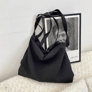 Detailed close-up of black pleated fabric tote bag with adjustable wide shoulder strap