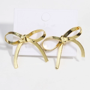 Detail of golden bow earrings with woven texture and silver needles on display card