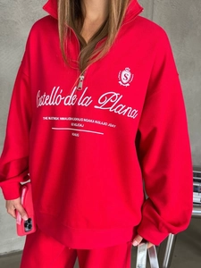 Detail of red half-zip sweatshirt featuring white embroidery and knitted texture finish