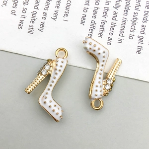 Macro detail of white enamel high heel charms with gold trim and inlaid rhinestones