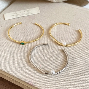 Détail d'un bracelet jonc plaqué or 18 carats avec pierre verte et perles blanches