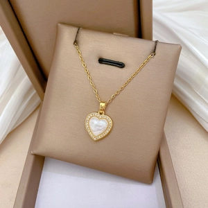 Detail of a gold heart necklace with white mother of pearl inlay and crystal pavé on silk