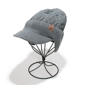 Détail du bonnet en maille grise avec protège-oreilles et patch logo en cuir brun