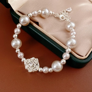 Close-up of pearl and zircon flower bracelet on dark green jewelry box