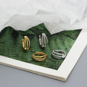 Detail of s925 silver triple-layered twisted hoop earrings in gold and silver finish