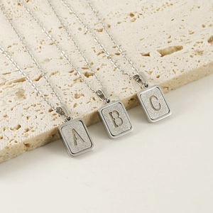 Dettaglio di collane in acciaio inossidabile argento con ciondoli incisi delle lettere A, B, C
