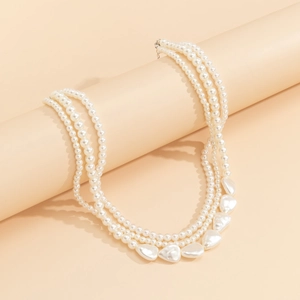 Detailed close-up of a three-layer pearl necklace with elegant heart-shaped pearl charms