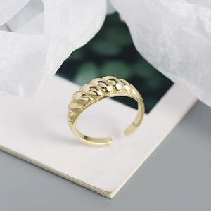 Detailed close-up of a golden twisted rope open ring placed on an open book