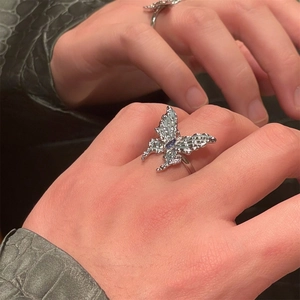 Close-up of silver butterfly ring with blue enamel and faux pearls on a finger