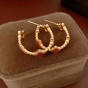 Detail of 18k gold plated clover C-shaped hoop earrings on a brown velvet jewelry box