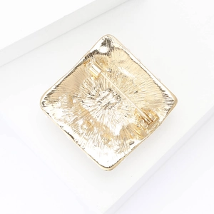 Detailed back view of gold square brooch showing safety pin clasp and textured finish