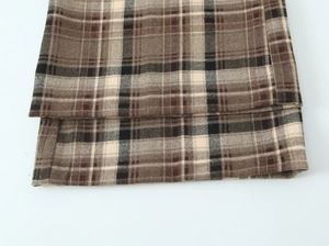 Détail d'un pantalon à carreaux marron avec coutures précises et tissu en tweed texturé