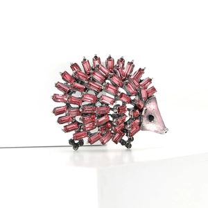 Macro detail of cute hedgehog brooch with pink crystals and dark metal finish