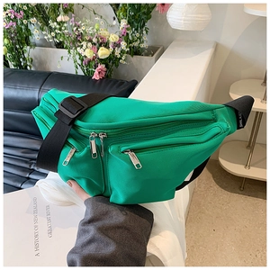 Close-up of bright green nylon crossbody bag with wide adjustable strap and zipper pockets