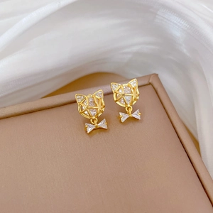Detail shot of gold cat-shaped earrings with clear crystals on silk display