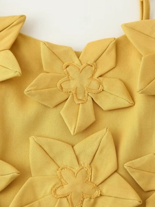 Détail de fleurs 3D en tissu jaune et broderies délicates sur cet ensemble femme