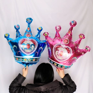 Detail of large blue and pink crown foil balloons held by a person for party decor