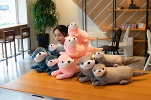 Detailed view of plush otter dolls in pink, blue, and grey on a wooden table cafe setting