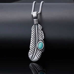 Detail of silver feather pendant featuring an oval turquoise stone on black background