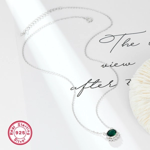 Detailed view of sterling silver necklace with green gemstone on coral decor