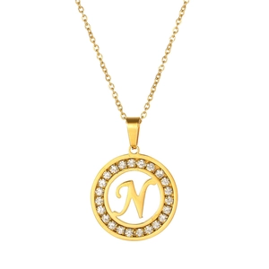 Detail of a gold circular necklace pendant with letter N and sparkling zircon inlay