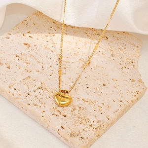Detailed view of 18K gold heart pendant necklace with Love engraving on stone