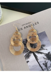 Detail of warm gold multi-layered twisted hoop earrings with a metallic finish