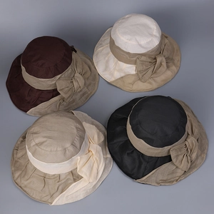 Detail view of four linen sun hats with large bows in brown, cream, tan and black