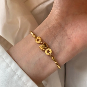 Detail of 18K gold plated bamboo bracelet with textured matelassé ball charm and engraving