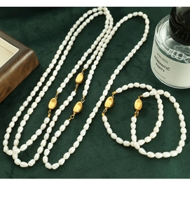 Detailed view of white baroque pearl necklace and bracelet set on green velvet fabric