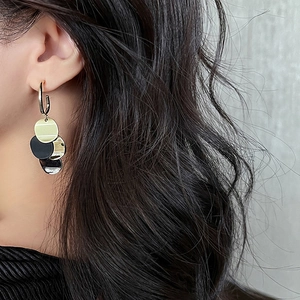 Boucles d'oreilles dorées en forme de C avec pendentifs ronds noirs sur mannequin