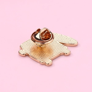 Detail of golden bicycle brooch back featuring butterfly clutch and textured finish