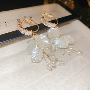Detail of gold floral earrings featuring zircon rings, white petals and pearl tassels