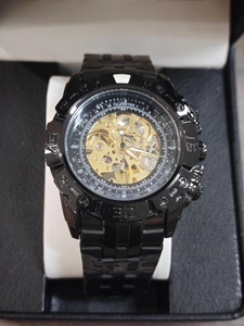 Macro detail of men's automatic watch showing black skeleton dial and golden mechanical gears