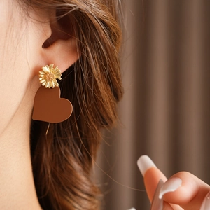 Detail of matte brown heart drop earrings with gold floral studs for a vacation style