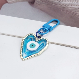 Close-up of a heart-shaped blue evil eye keychain with gold metal frame and blue clip