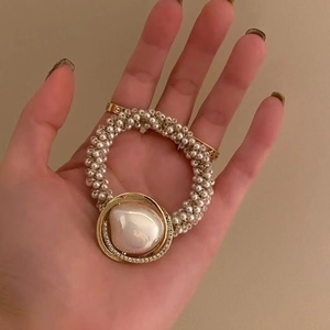 Elegant pearl hair tie with large rhinestone-studded gold ring and central baroque pearl