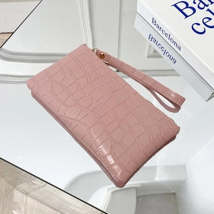 Pink crocodile pattern wristlet clutch bag with metal zipper on a mirrored surface