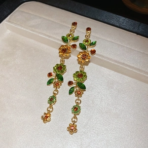 Detail langer Blumen-Ohrhänger mit grünen und bernsteinfarbenen Strasssteinen in Gold