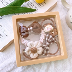 Detail of 4-piece hair accessory set in a cream display box with a cozy lifestyle setting
