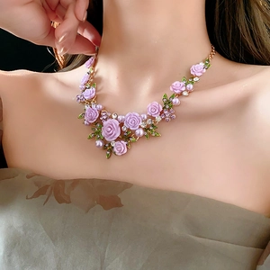 Détail du collier floral avec fleurs mauves et perles sur le cou du mannequin