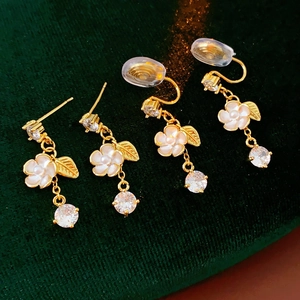 Macro view of gold plated flower earrings with tassels on green velvet background