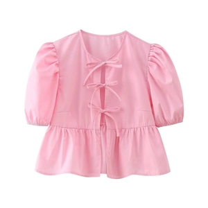 Detailed view of pink puff sleeve top with delicate ribbon bows and ruffled hemline