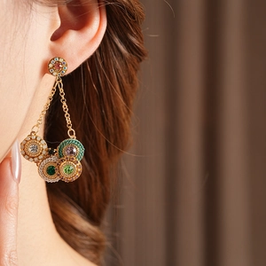 Détail de boucles d'oreilles vintage dorées avec pierres colorées et perles sur modèle