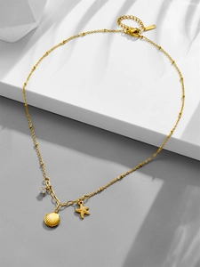 Detail of 18k gold plated starfish and shell pendant necklace with zircon on a summer background