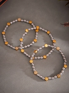 Detailed view of three-piece beaded bracelet set with silver hammered beads and gold flowers