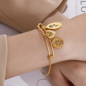 Adjustable gold charm bracelet with rose and heart pendants on a model's wrist