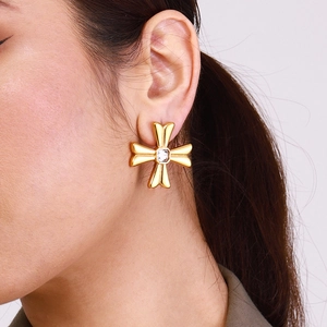 Elegant gold cross stud earrings with white zircon on ear model for a minimalist look