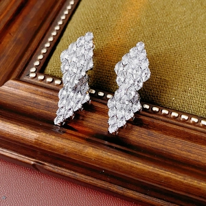 Macro shot of silver zircon leaf-shaped earrings on a vintage wooden frame backdrop
